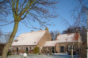 De boerderij vanaf de achterzijde gezien in de winter met frisse sneeuw op de daken